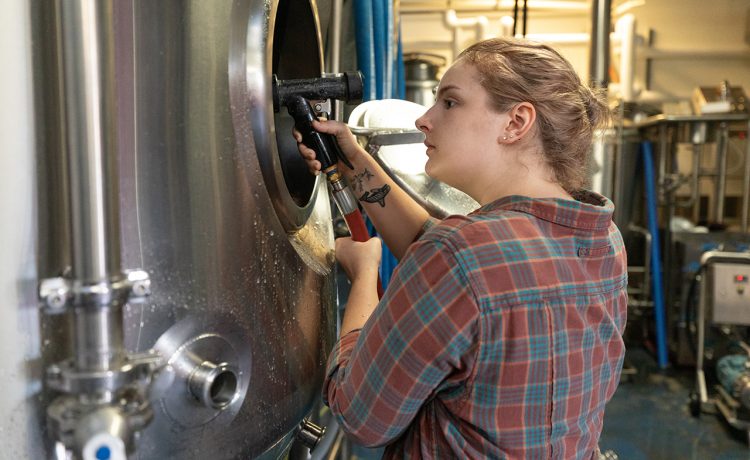 student prepares a brewing vat for beer