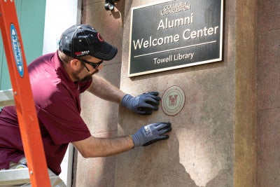 A worker installs a medallion on towell library