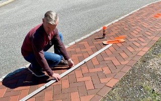 walter cain spray paints bricks orange to demonstrate the 6 feet recommendation for social distancing