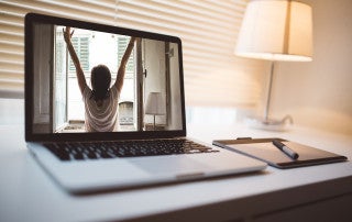 laptop on a desk with a woman on the screen doing yoga