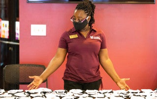 woman hands out face masks at stern student center