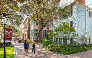students walk past buildings on the college of charleston campus