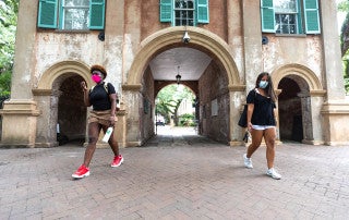 students wearing face masks walk on the college of charleston campus