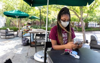 a student wearing a mask uses a cell phone