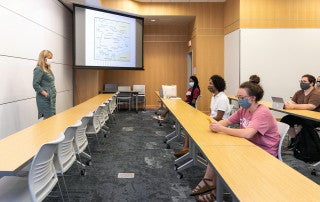 A professor stands in front a class. everyone is wearing face masks for covid safety