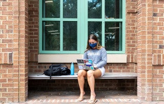student wears a mask while working on a laptop