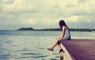 girl sits on a dock looking out on a lake