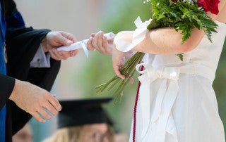 a faculty member hands a female graduate a diploma