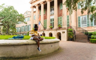 a girl sits on the cistern at the college of charleston campus