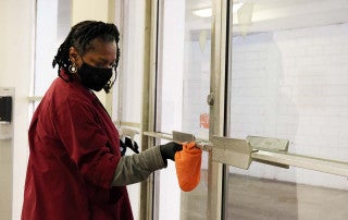 Barbara Simmons cleans a door in college lodge residence hall