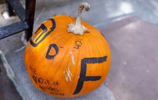 "The ghosts if Grades Past" halloween pumpkin sits on the steps of the Honors College.