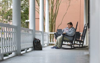 student john broome studies on the porch of the honors college