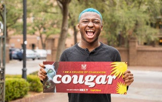 a student holds a cougar sign
