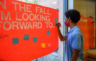 a student signs a message board in berry hall