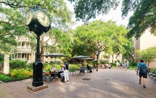students sit near a large clock on the college of charleston campus
