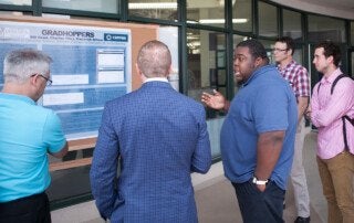 students talk at a poster session highlighting research projects