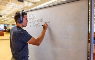 a student does a math problem on a white board