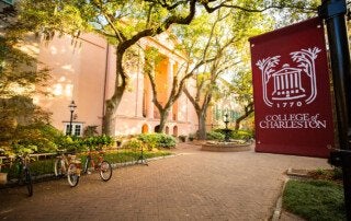 building with trees and lamppost banner of college of charleston logo