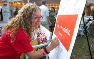 yes i'm a feminist event; a woman signs a poster