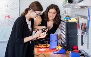 jo jackley and sarah schoemann work on building a computer device