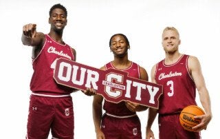 men's basketball team members hold a sign and basketball
