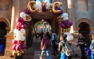 students walking by balloons reading cofc on the college of charleston campus