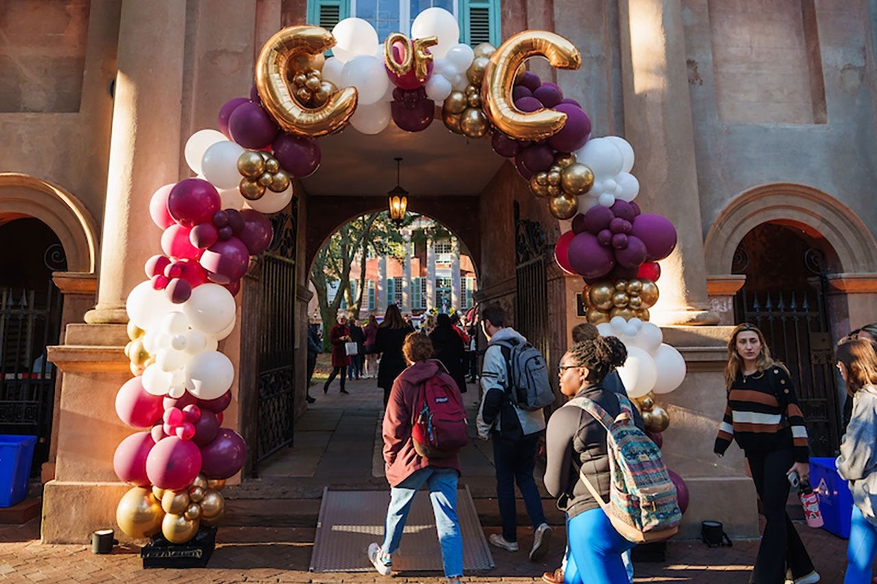 students walking by balloons reading cofc on the college of charleston campus