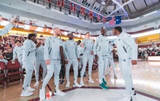 Men's basketball players cheer after learning they'll take on San Diego State.