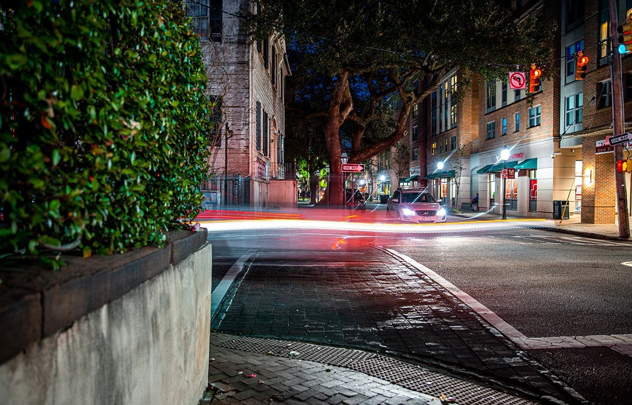 cars speed by on George St. at night