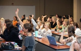 students raising their hands in a classroom