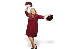 a woman wearing a maroon dress holds pompoms