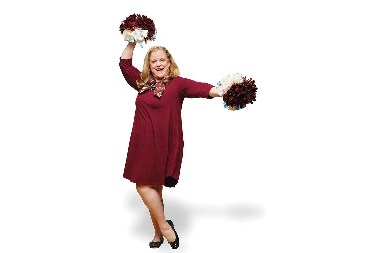 a woman wearing a maroon dress holds pompoms