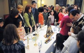 people gathered around a table with menorahs