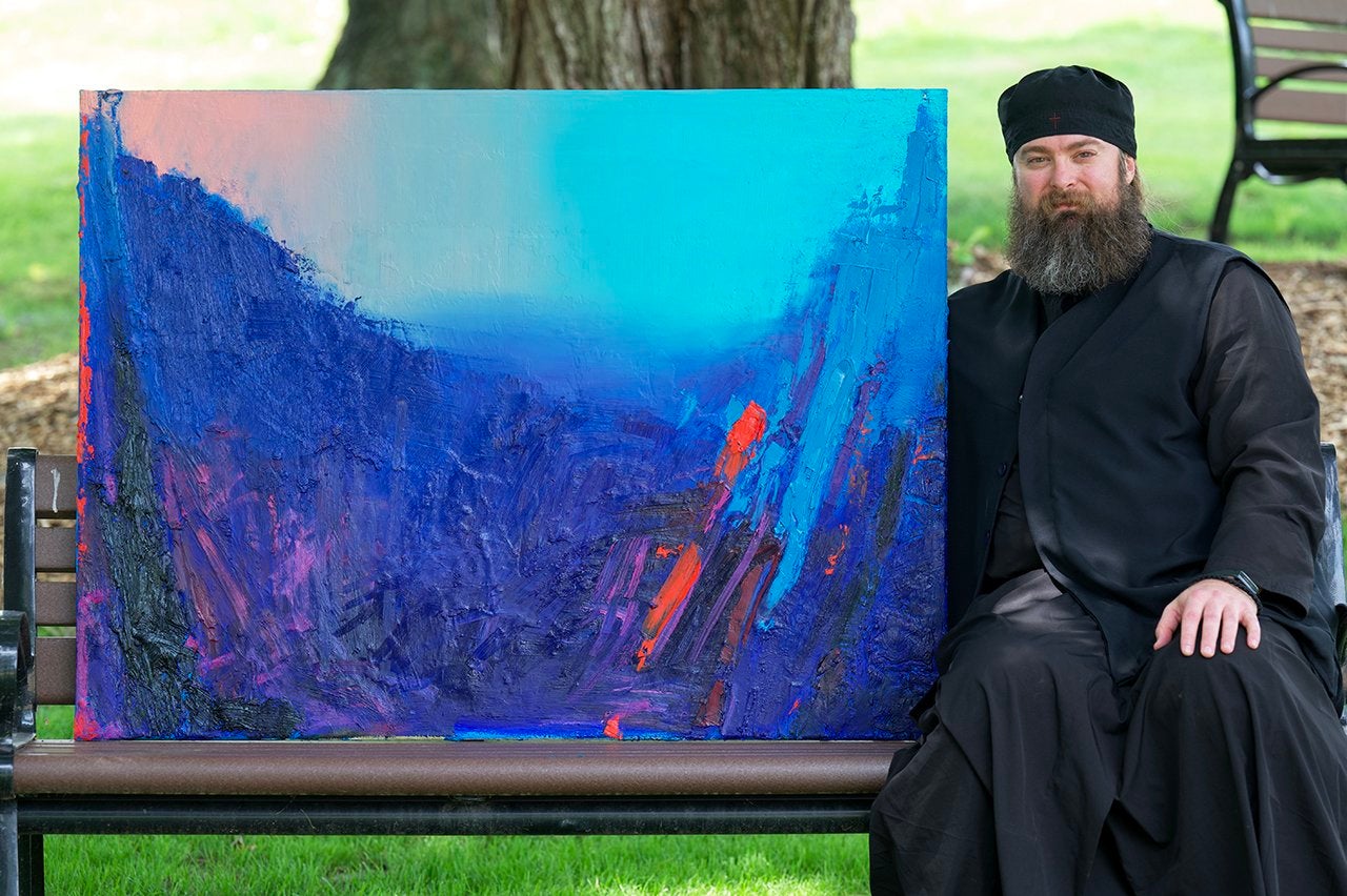 father george davis sits on a bench with a bright blue painting