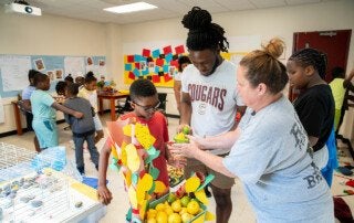 two teachers work with a student on a lemon and lime tree craft