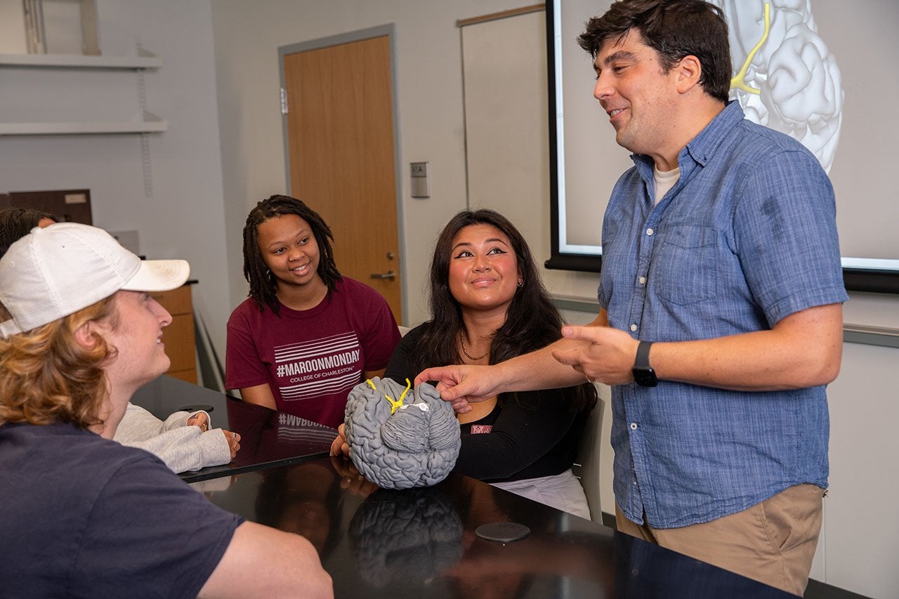 Nick Hindy holds a brain model and talks to students